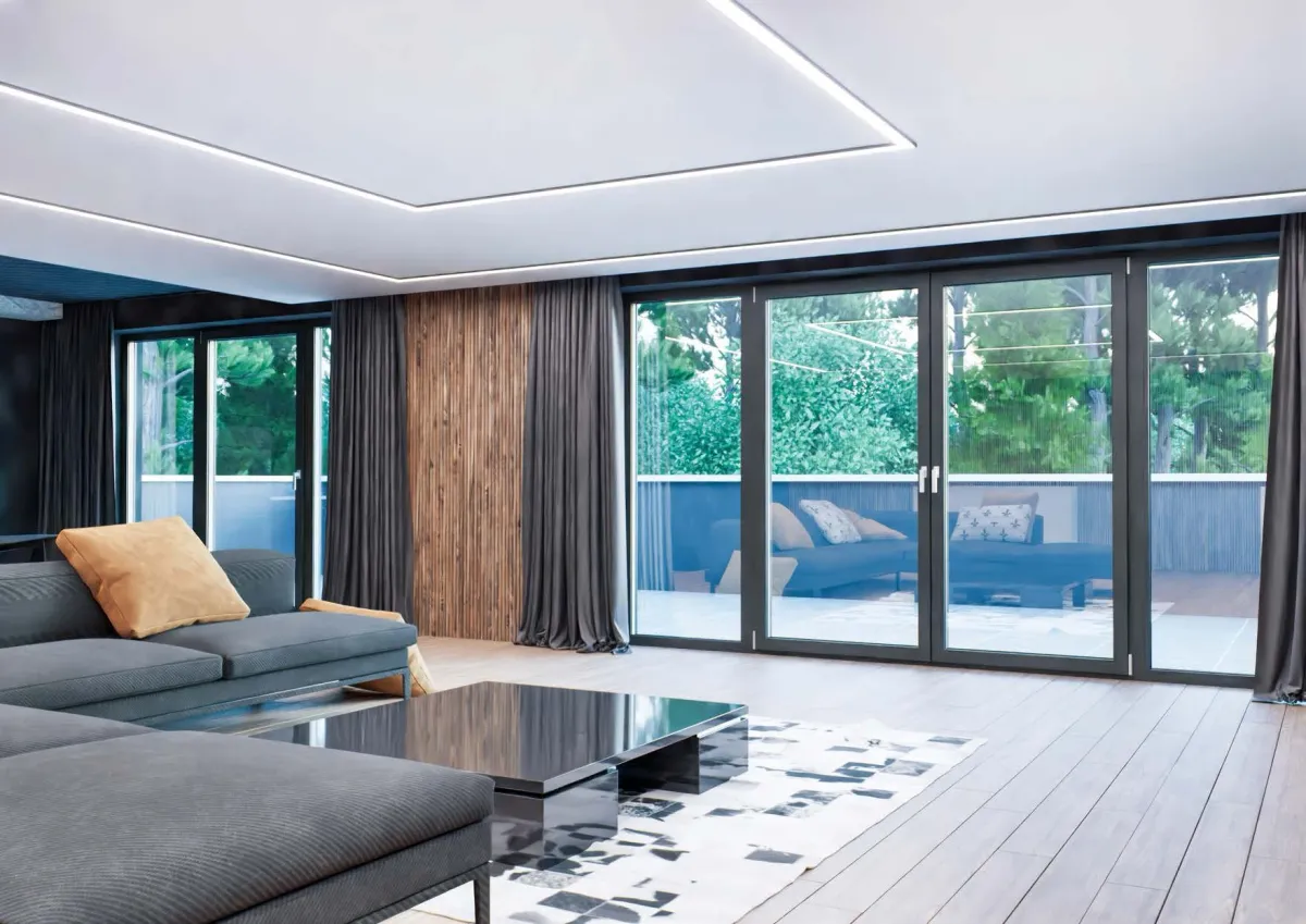 Salon avec une grande baie coulissante anthracite donnant sur le jardin