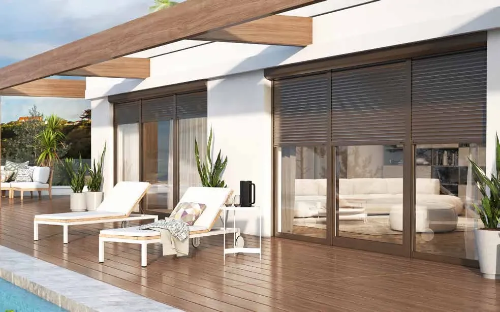 Terrasse au bord d'une piscine, grandes baies vitrées équipées de volets roulants